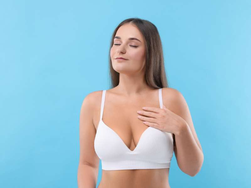 Mulher com sorriso confiante, de perfil, com roupas que valorizam a nova silhueta após a mamoplastia.