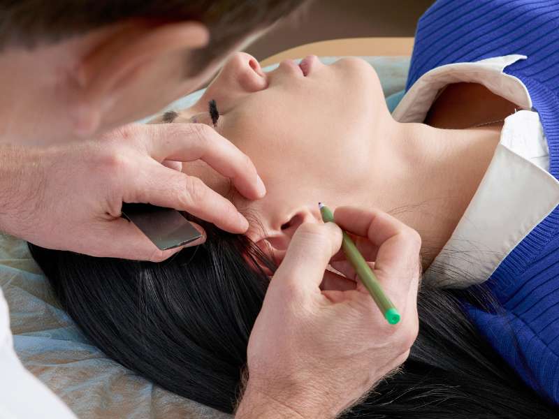 Otoplastia: o que é e como pode melhorar a sua aparência 1 Close-up de um cirurgião plástico experiente examinando a orelha.